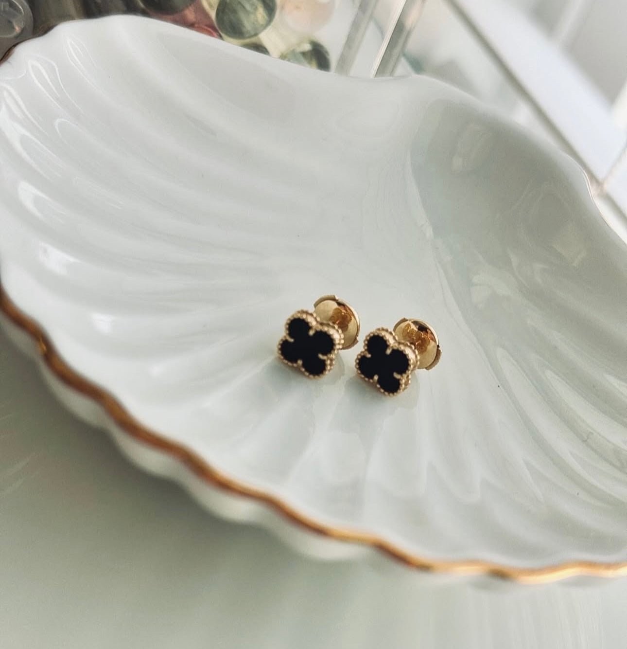 Striking contrast of deep black onyx stones and radiant 18k gold in a lucky four-leaf clover earring design.